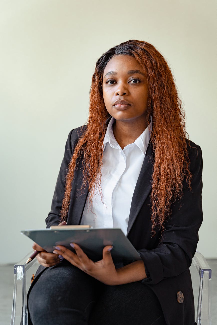 woman in black blazer holding a clipboard