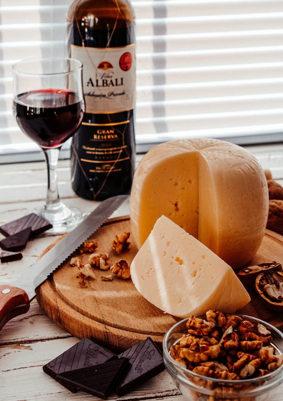 cheese and wine on brown wooden chopping board