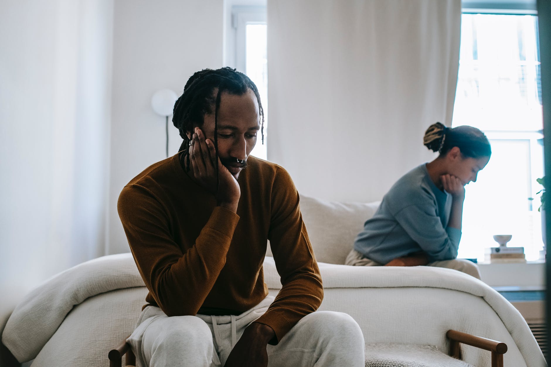 upset black couple sitting apart at home