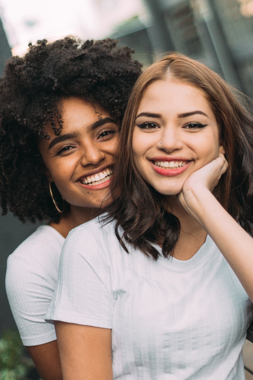 photo of two women smiling wearing white shirt